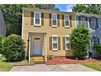 Charming two-story townhouse featuring a classic design with yellow siding and green shutters, surrounded by lush greenery at 4120 Buckley Woods Dr, Norcross, GA 30093