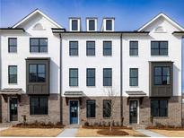 Charming townhome exterior featuring brick accents and modern window design under a clear blue sky at 4231 Millcroft Pl # 207, Buford, GA 30518