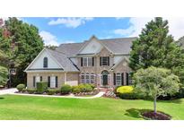 Beautiful two-story brick home with a manicured lawn, lush landscaping, and a classic architectural design at 5357 Harbury Cv, Suwanee, GA 30024