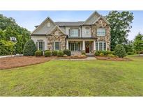 Beautiful two-story home featuring a stone facade, manicured lawn, and inviting front porch at 10 Nesbit Reserve Ct, Atlanta, GA 30350
