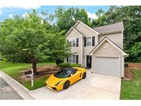 Two-story home featuring a tan exterior, black shutters, manicured lawn and a striking yellow luxury car in the driveway at 248 Springbottom Dr, Lawrenceville, GA 30046