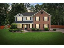 Charming two-story home with brick and siding, surrounded by a lush green lawn and mature trees at 5399 Emily Cir, Ellenwood, GA 30294