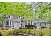 Charming two-story home with gray siding, manicured landscaping, and a welcoming front porch at 115 Leaf Lake Dr, Suwanee, GA 30024