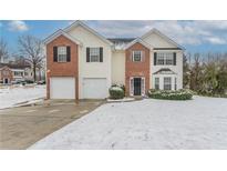 Two-story home featuring a two-car garage and a well-manicured lawn partially covered in winter snow at 3870 Golfe Links Dr, Snellville, GA 30039