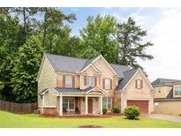 Charming two-story brick home with a well-manicured lawn, inviting front porch, and attached garage at 1110 Cureton Dr, Austell, GA 30106