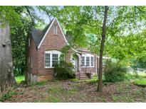 Charming brick home features an arched front door, white trim, and is surrounded by mature trees at 1699 Emerald Sw Ave, Atlanta, GA 30310