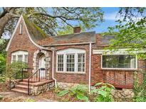 Charming brick home featuring a stone-arched entryway and multiple windows for ample natural light at 1699 Emerald Sw Ave, Atlanta, GA 30310