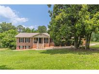 Charming brick home with a well-manicured lawn, mature trees, and inviting front porch with brick steps at 7928 S Giles Rd, Douglasville, GA 30135