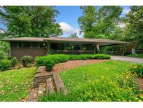 Charming brick home with manicured landscaping, flowering plants and a covered carport at 1138 Berkeley Rd, Avondale Estates, GA 30002