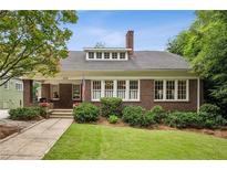 Charming brick home with a well-manicured lawn and an inviting front porch, showcasing classic architectural details at 1371 N Highland Ne Ave, Atlanta, GA 30306