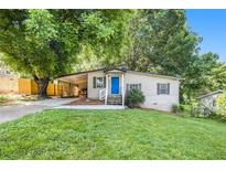 Charming home featuring a bright blue front door, carport, landscaped yard, and mature trees at 1636 Mary George Nw Ave, Atlanta, GA 30318