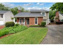 Charming home with a brick facade, well-maintained lawn, and attached garage at 303 Roswell Green Ln, Roswell, GA 30075
