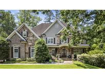 Charming two-story home with a stone and brick facade, lush landscaping, and a covered front porch at 157 Lake Forrest Ne Ln, Atlanta, GA 30342