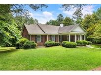 Charming one-story brick home featuring a well-manicured lawn and lovely landscaping at 11270 Stroup Road, Roswell, GA 30075