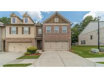 Charming brick townhome featuring a two-car garage and a well-maintained lawn with lush greenery at 3255 Clear View Dr, Snellville, GA 30078