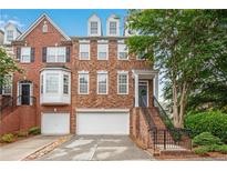 Charming brick townhome with a two-car garage and manicured landscaping at 451 Tioram Se Ln, Smyrna, GA 30082