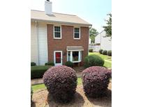 Charming brick two-story townhome featuring a bay window and neatly manicured shrubbery in the front yard at 210 Mill Creek Pl, Roswell, GA 30076