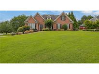 Charming brick home features a well manicured front yard and mature landscaping at 1304 Swallows Walk, Grayson, GA 30017