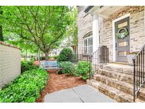 Charming brick home entrance featuring landscaped garden, a blue bench and a decorative front door at 4202 Deming Cir, Sandy Springs, GA 30342