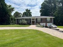 Charming brick home featuring a two-car garage, a spacious lawn, and a patterned brick driveway at 3962 Chicamauga Ne Dr, Kennesaw, GA 30144