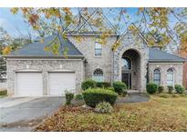 Charming brick home features an attached two-car garage, a stone portico and manicured landscaping at 185 Beracah Sw Walk, Atlanta, GA 30331