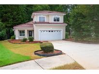Charming two-story home boasts a lush front lawn, manicured shrubbery, and a convenient two-car garage at 128 Garden Walk, Stockbridge, GA 30281