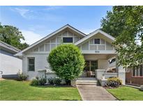 Charming bungalow featuring white painted brick, a manicured lawn, mature tree, and inviting front porch at 504 Angier Ne Ave, Atlanta, GA 30308