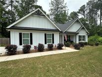 Charming one-story home featuring a landscaped yard, white siding, black shutters, and a welcoming front porch with rocking chairs at 2751 Pilgrim Mill Rd, Cumming, GA 30041