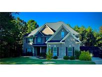 Beautiful two-story brick home with lush lawn, mature trees and inviting covered front porch at 704 Kenton Ct, Locust Grove, GA 30248