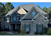 Beautiful two-story brick home featuring a well-manicured lawn and complemented by mature trees against a bright blue sky at 704 Kenton Ct, Locust Grove, GA 30248