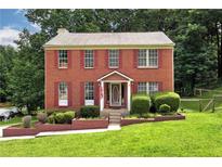 Charming brick home featuring red shutters, a well-manicured lawn and beautiful landscaping at 2621 Garland Way, Duluth, GA 30096