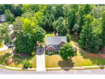 An attractive two-story brick home with a lush lawn and mature trees on a private, wooded lot at 1120 Bagwell Dr, Kennesaw, GA 30152