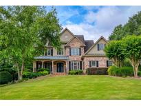 Charming brick and siding home with a manicured lawn and lush landscaping at 9035 Brixham Ct, Suwanee, GA 30024