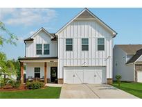 Charming two-story white farmhouse with a well-manicured lawn and a two-car garage at 701 Woodward Ct, Canton, GA 30114