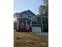 Two-story home with navy siding, white trim, a red porch, an attached two car garage and nice landscaping at 102 Neal Ave, Stockbridge, GA 30281