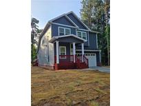 Charming two-story home with blue siding, white trim, and a red porch, nestled among tall trees at 102 Neal Ave, Stockbridge, GA 30281