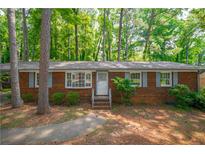 Charming brick home with a well-maintained lawn and mature trees at 1671 Drayton Woods Dr, Tucker, GA 30084