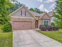 Charming home featuring a stone facade, two-car garage, manicured lawn, and meticulously maintained landscaping at 105 Silver Trce, Dallas, GA 30157