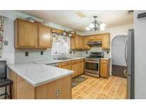 Well-lit kitchen features wood cabinets, wood floors, a gas range and a granite countertop on the breakfast bar at 493 Whaleys Lake Dr, Jonesboro, GA 30238