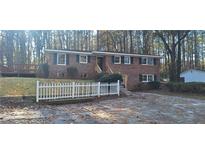 Charming brick home featuring a manicured lawn, white picket fence, and mature trees at 2289 Addison Rd, Marietta, GA 30066