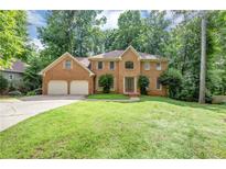 Stately brick home featuring a two-car garage and lush green lawn at 11575 Wildwood Springs Dr, Roswell, GA 30075
