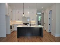 Modern kitchen features white cabinets, wooden floors, black island and stainless steel appliances at 293 White St # 2, Marietta, GA 30060