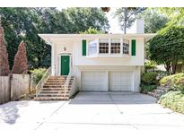 Charming white home featuring a green front door, a two-car garage, and lush landscaping at 746 Gladstone Nw Rd, Atlanta, GA 30318