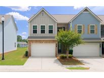 Charming townhome featuring a two-car garage and well-maintained landscaping at 191 Madison Bnd, Woodstock, GA 30188