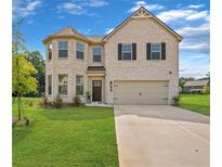 Charming two-story brick home with a two-car garage and well-manicured lawn at 49 Ryder Pass Way, Loganville, GA 30052