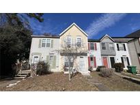 View of the townhome's front exterior featuring varying paint colors and some landscaping at 497 Prince Of Wales, Stone Mountain, GA 30083