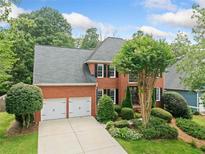 Lovely two-story brick home with a two-car garage and a beautiful landscaped front yard at 530 Summerhill Dr, Roswell, GA 30075