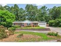 Charming brick home with a lush front yard, mature trees and solar panels on the roof at 3292 Ferncliff Ne Pl, Atlanta, GA 30324
