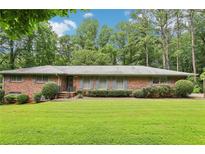Charming one-story brick home with a lush green lawn and mature trees creating a serene setting at 415 Haven Ln, Marietta, GA 30066