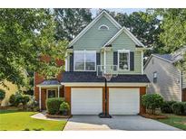 Charming two-story home with a brick-and-green facade, attached garage, and well-maintained landscaping at 4284 Cabretta Se Dr, Smyrna, GA 30080